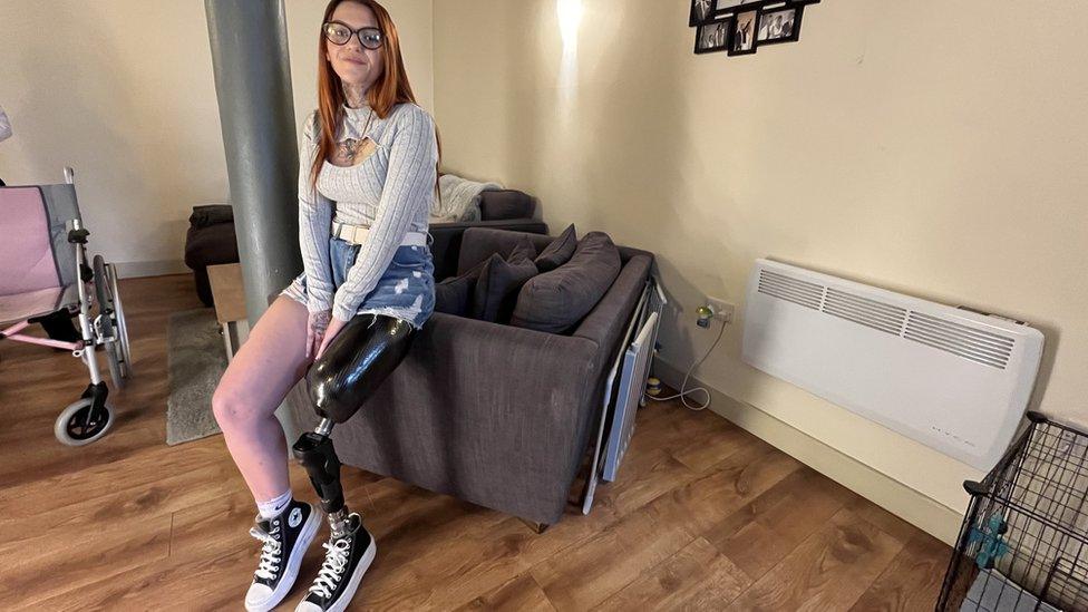 Woman with prosthetic leg sitting on sofa