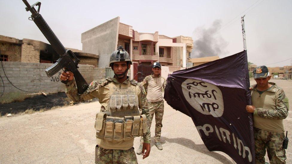 Iraqi government soldiers hold an so-called Islamic State flag after a battle in Fallujah.