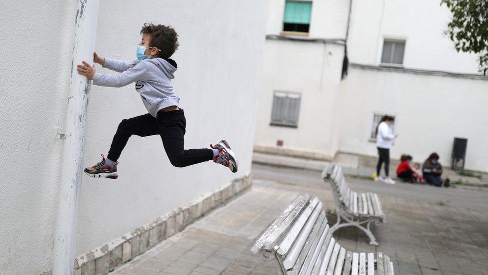 Kilian, 6, wears a protective face mask as he jumps from a bench, after restrictions were partially lifted for children, during the coronavirus disease (COVID-19) outbreak, in Igualada, Spain April 26, 2020.