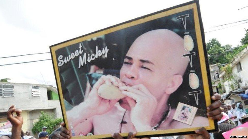 Supporters of Haitian popular singer, and presidential candidate Michel Joseph Martelly hold a poster with his image on October 20, 2010 in Port-au-Prince during a rally.