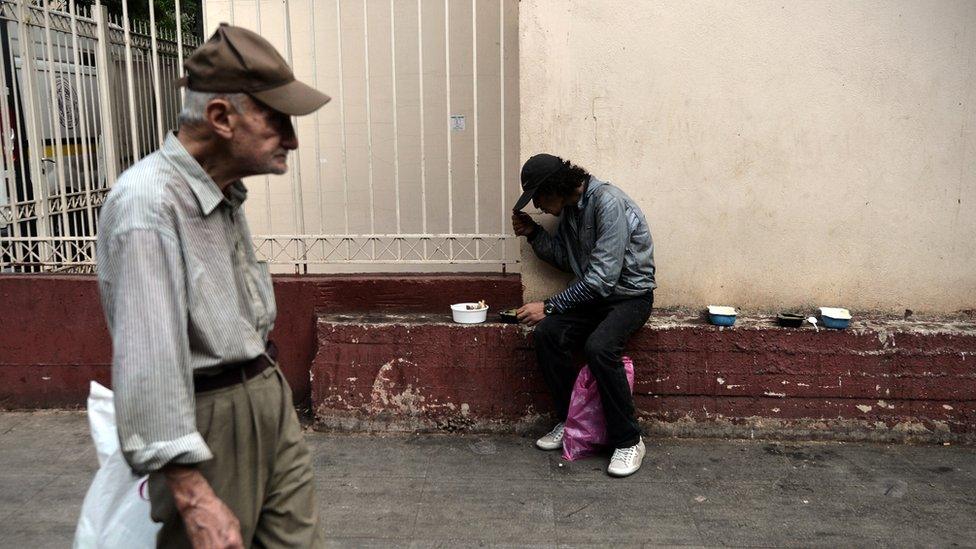 A man eats after he received food offered by the Greek church in central Athens