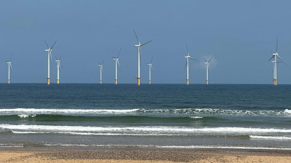 Wind turbines out at sea pictured from a beach