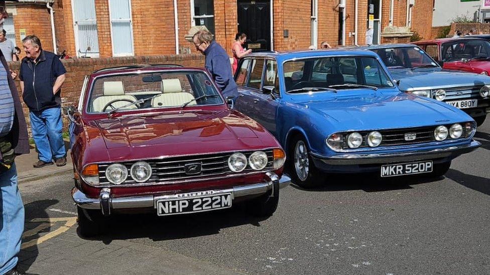 A burgundy Triumph Stag Convertible next to a blueTriumph 2500s Estate