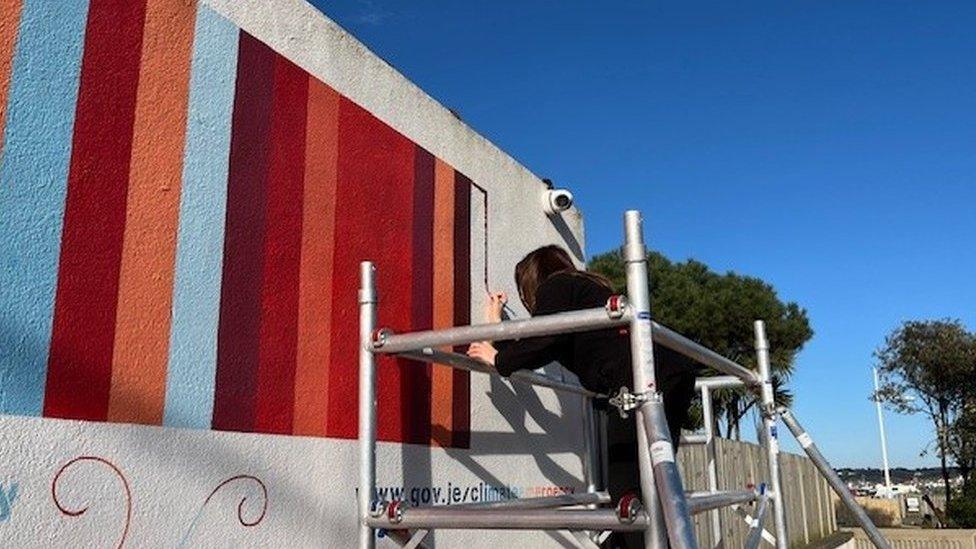 Woman painting the 130th strip on the wall