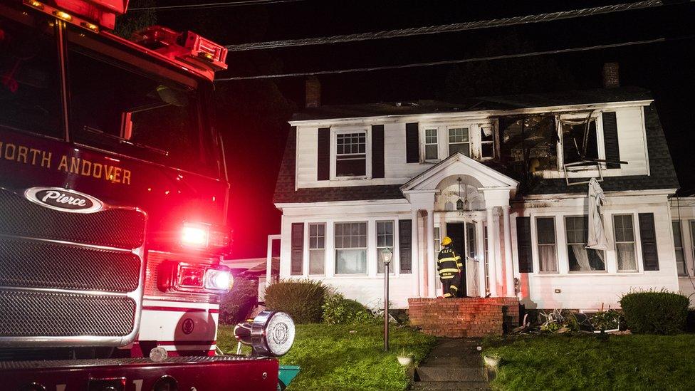 Fire truck is seen next to large house with visible explosion point on upper floor