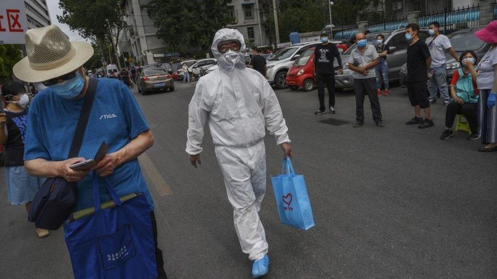 A health worker in Beijing holds a blue carrier bag