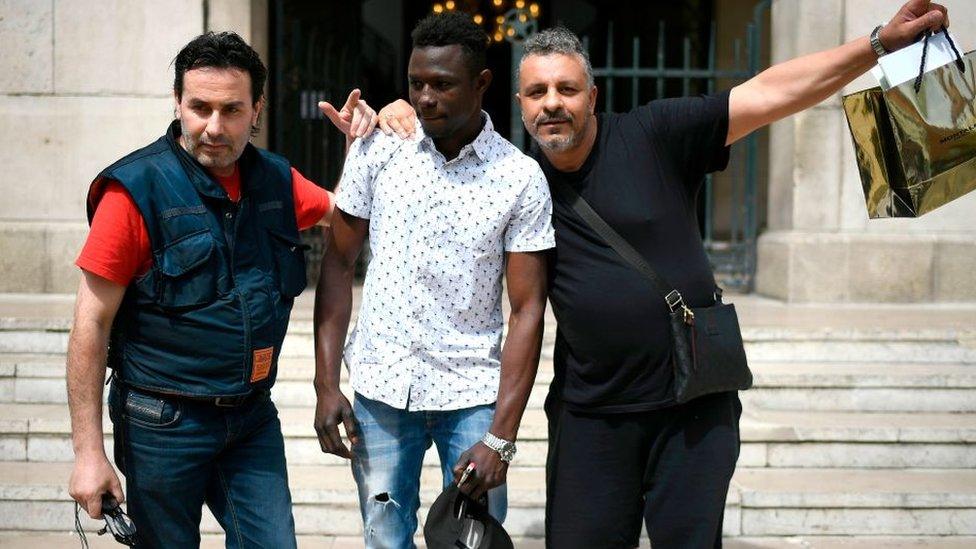 A 22-year old Mamoudou Gassama from Mali (C) poses with passers-by in front of the town hall of Montreuil, an eastern Paris suburb, on May 28, 2018