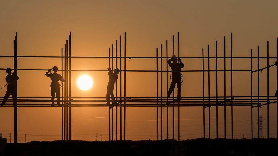 Image of building workers against teh sun