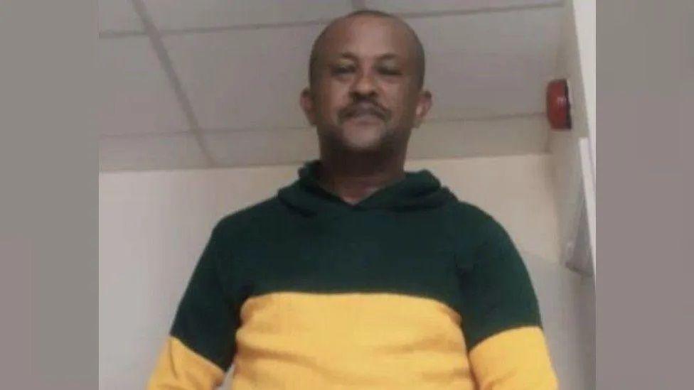 Kidane Gebrehiwot, who was killed in Gloucester last year. The picture is taken from below and shows Mr Gebrehiwot smiling slightly at the camera. He is wearing a green and yellow hoodie.