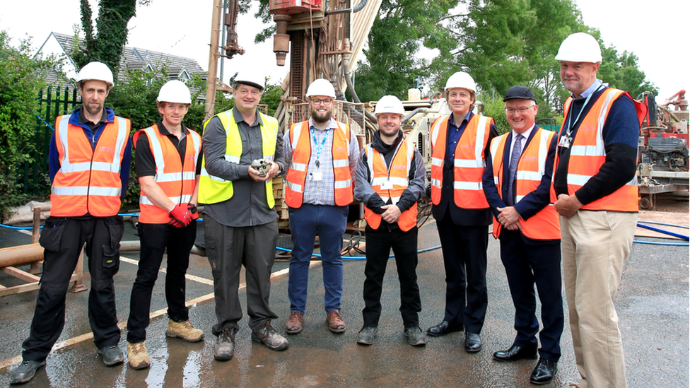 Men proudly standing in front of a boring machine