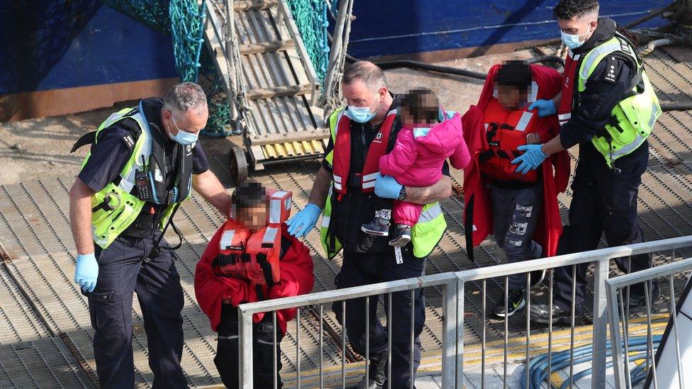 Three young children and a woman (right), thought to be a migrants, are brought ashore by Border Force officers at Dover marina in Kent