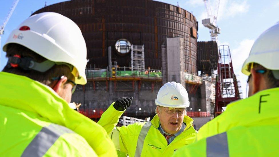 Boris johnson in hi-viz with a power plant in the background