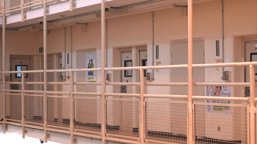 A hallway inside HMP Woodhill that has cell doors coming off it.