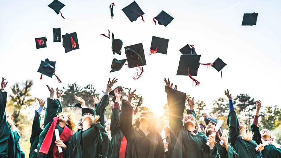 Students celebrating their graduation day while throwing their caps up in the air.