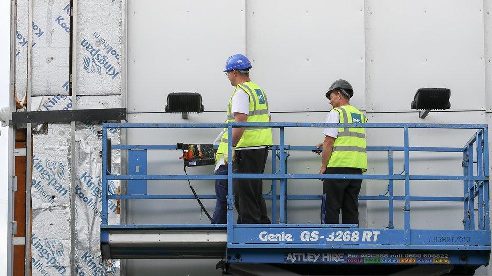 Workers remove cladding for testing from a tower blocks in Salford City