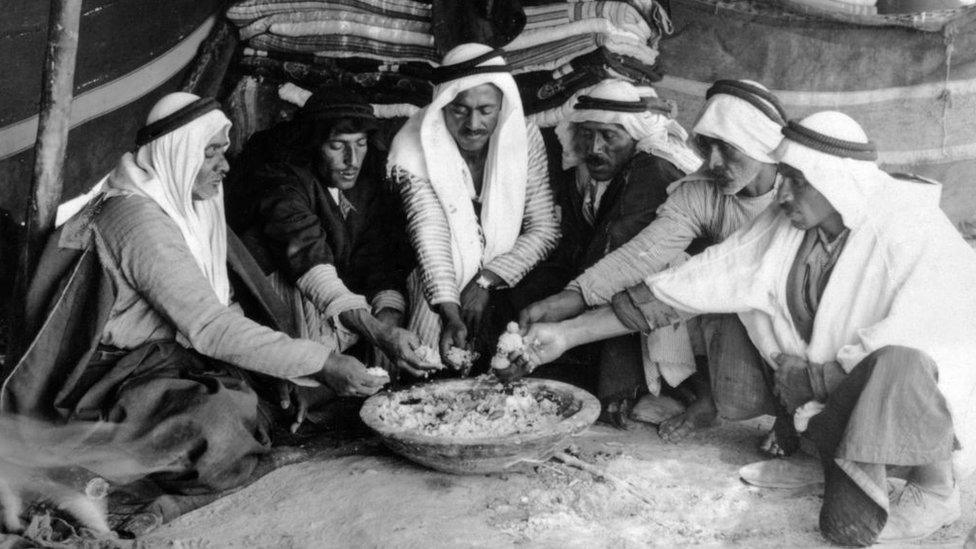 A group of six Arab men share a meal in Jericho, Palestine, in about 1925