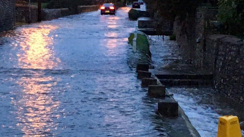 A car drives down a flooded main road in Llanblethian.