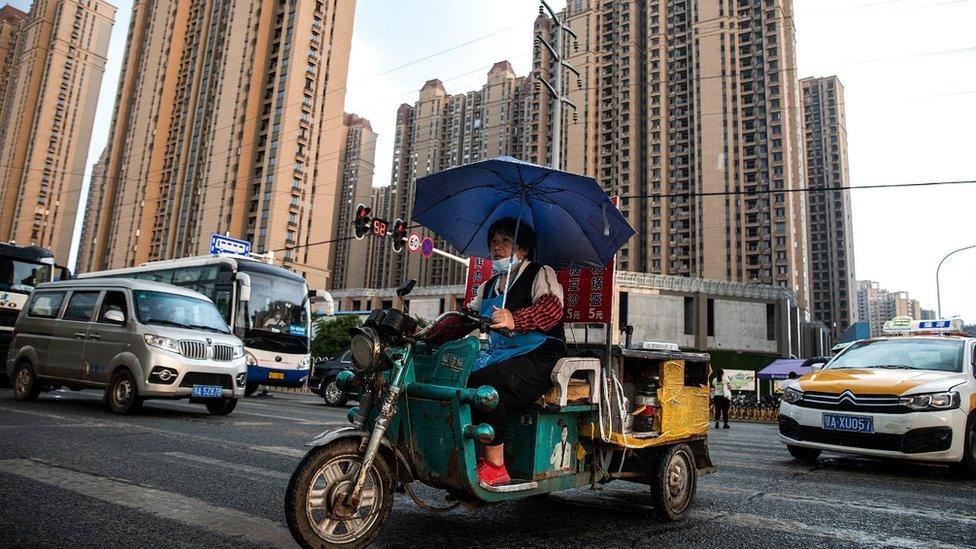 A vendor cycles through the Evergrande changqing community in the rain on September 24, 2021.