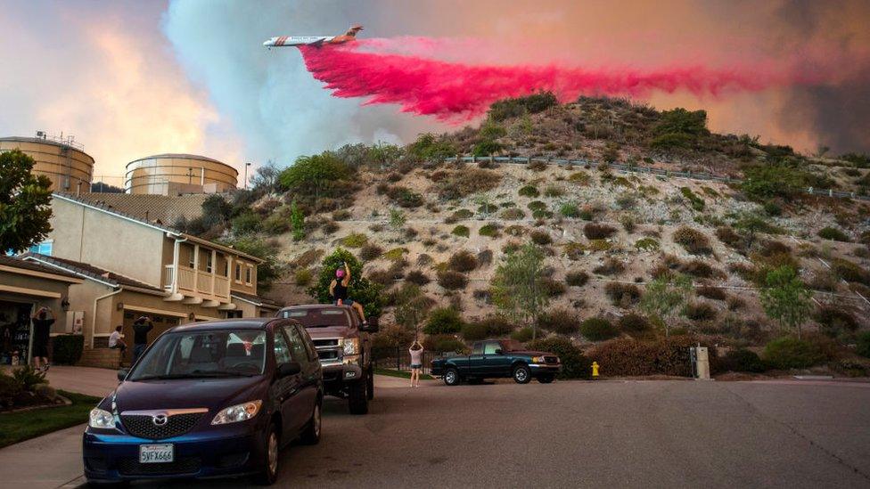 A plane drops retardant over a home