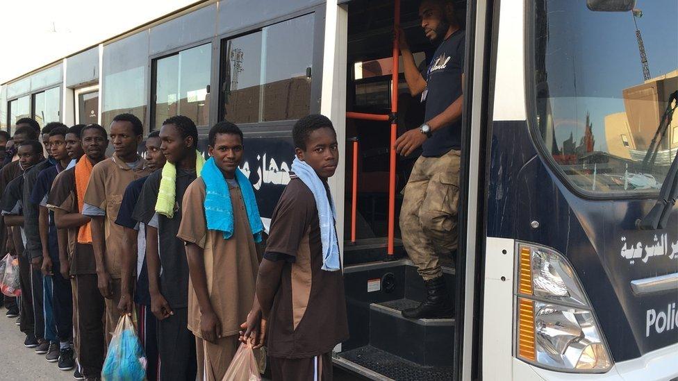 Gambian men being deported from Abu Salim Detention Centre, outside Tripoli, queue for buses