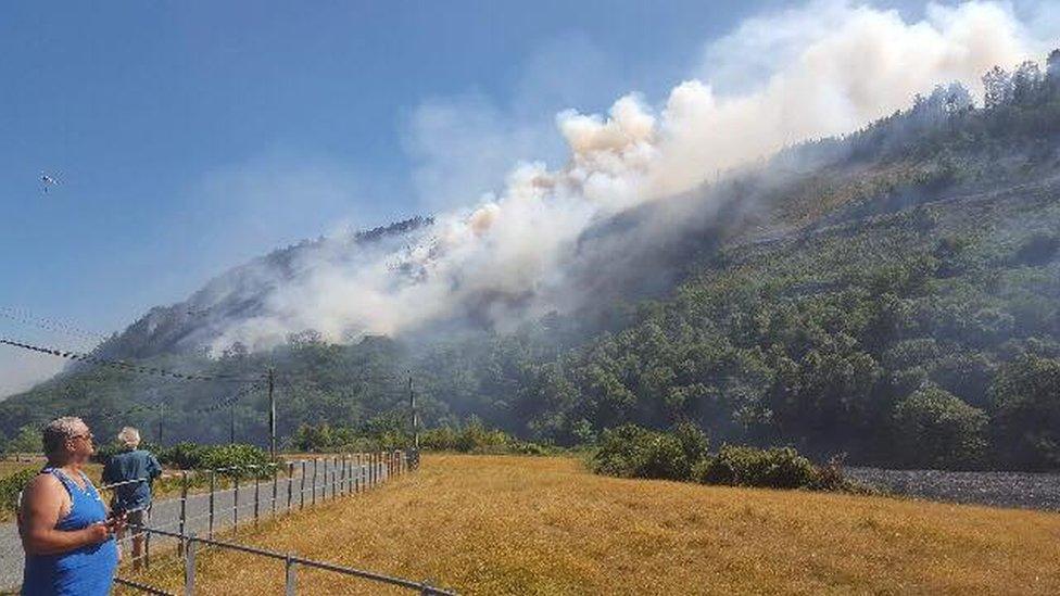 Man watches as fire rages on the hillside