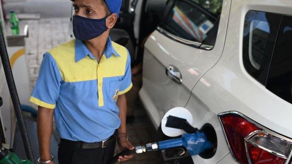 A worker fills up the tank of a car with diesel at a petrol station in New Delhi