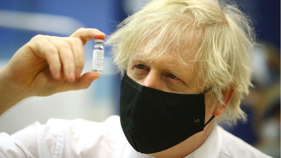 Boris Johnson holding a vial of vaccine