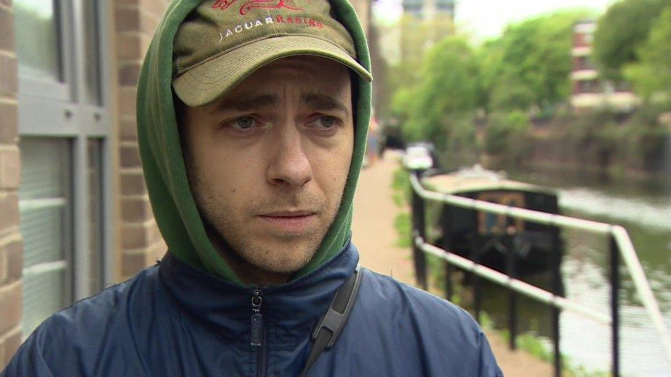 Image of Marcel wearing a khaki cap, green hoodie and blue coat. in front of the canal.