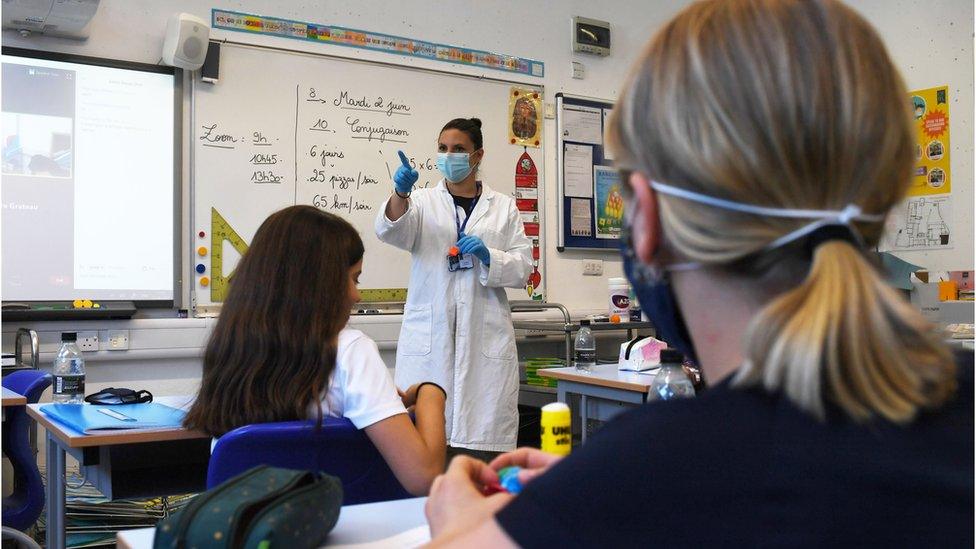 girl in classroom teacher wears mask