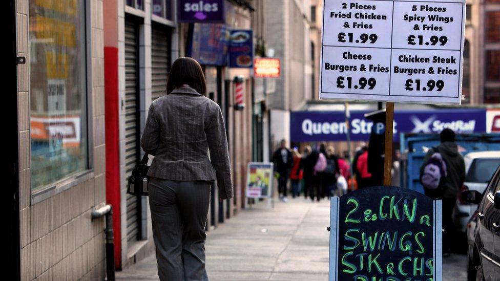 woman walks past a chip shop