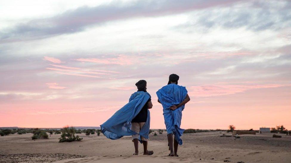 Two men walk in the desert of Guelb El Jmêl, in the eastern Mauritania on November 21, 2018.