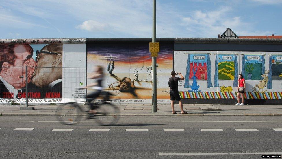 Visitors look at murals that decorate a surviving portion of the Berlin Wall known as the East Side Gallery on July 7, 2009 in Berlin, Germany