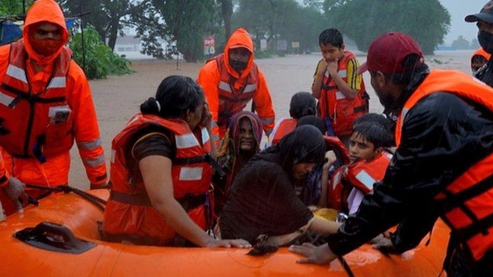 Rescuers carry resident from flooded areas in a dinghy, western India, July 2021