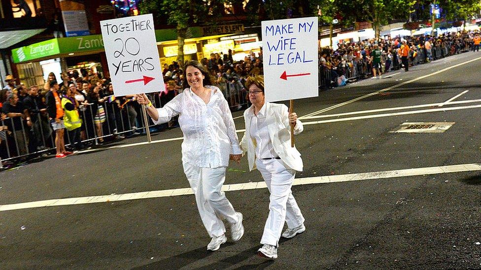 A couple carrying placards at the Mardi Gras in 2013