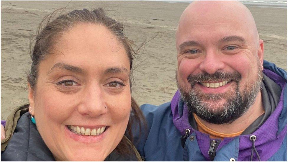 Woolsack Race organisers Kirsten and Danny Toft are pictured smiling on a beach together