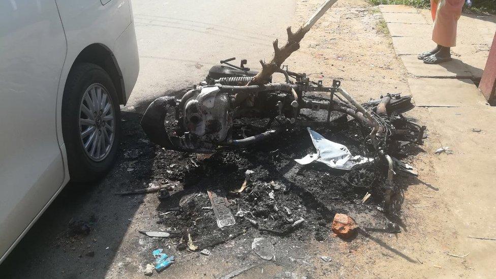 A motorbike frame is abandoned in the street after it was burned in street clashes in Galle province, Sri Lanka