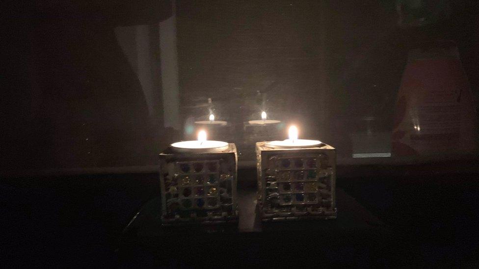 A pair of candles shine brightly in a dark room to commemorate Kristallnacht