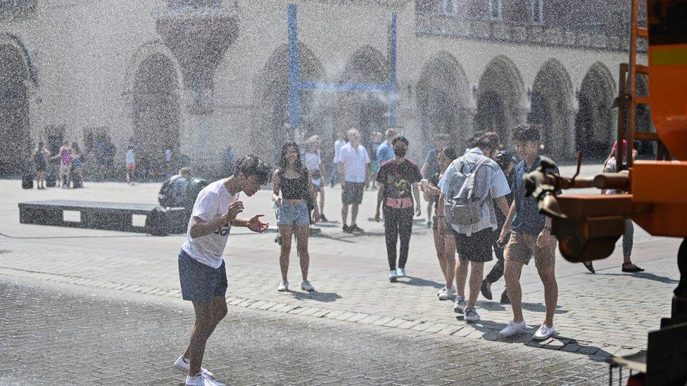 A truck sprays a curtain of water to help people cool down in a square in Krakow, Poland