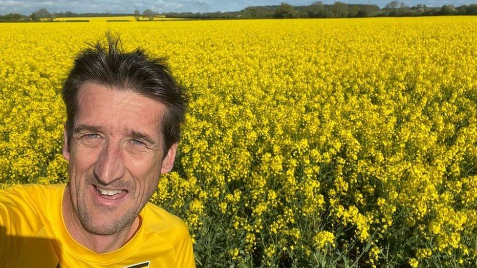 Rob Walker in front of a field of yellow plants