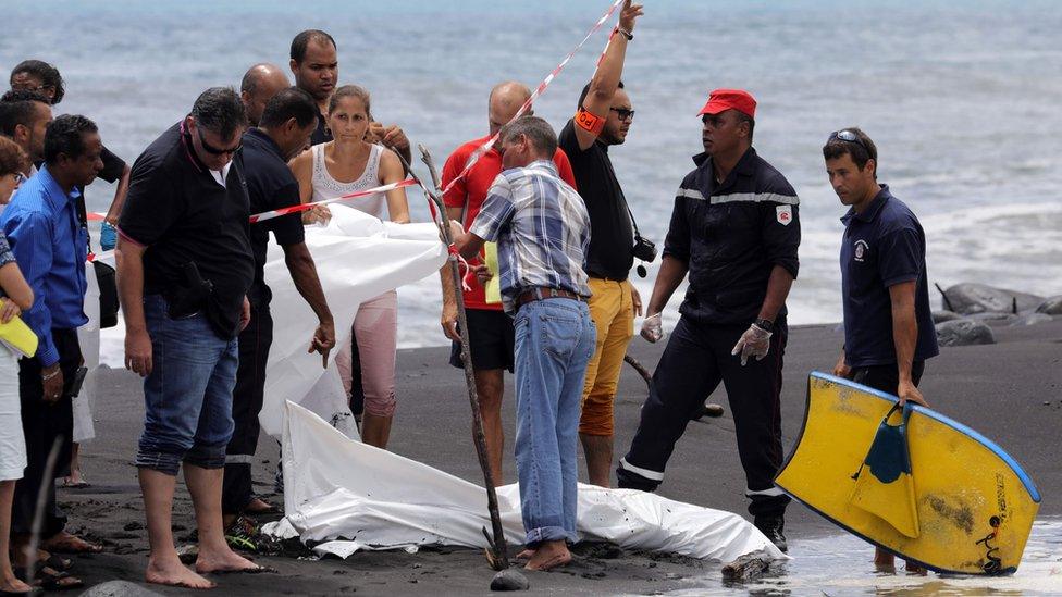 Police, firefighters and others stand next to the body of a body-boarder killed by a shark, covered by a white cloth, on 21 February 2017 on a beach in Saint-Andre, on the French island of Reunion in the Indian Ocean