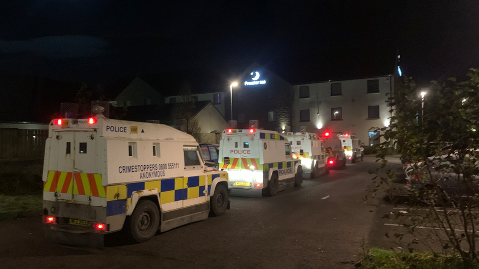 Five police Land Rovers parked in front of a Premier Inn