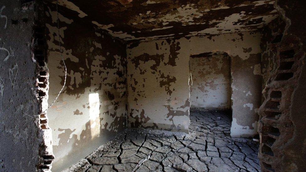 the inside of a house with cracked mud on the floor