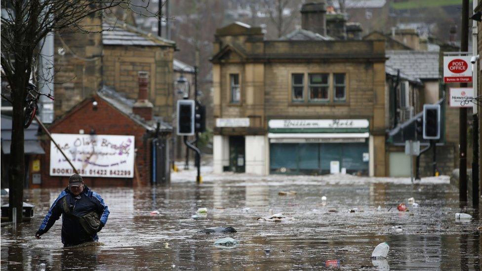 Man wades through water in Hebden Bridge