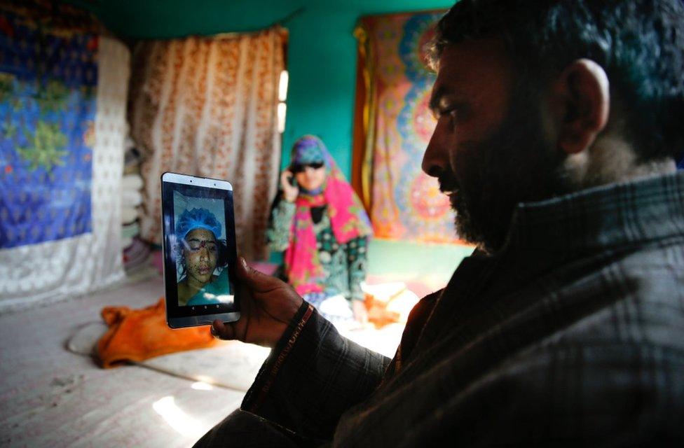 Insha's father looks at a picture of her in hospital