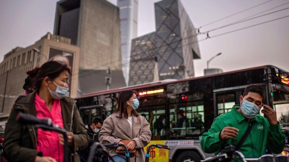 A woman (C) wearing a face mask as a preventive measure against the Covid-19