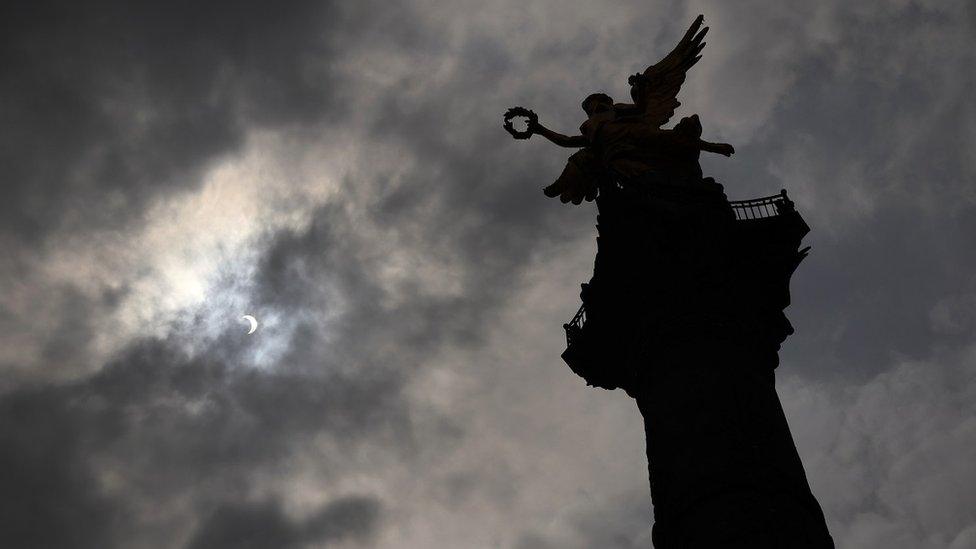 Monument in Mexico City with partial eclipse behind it.