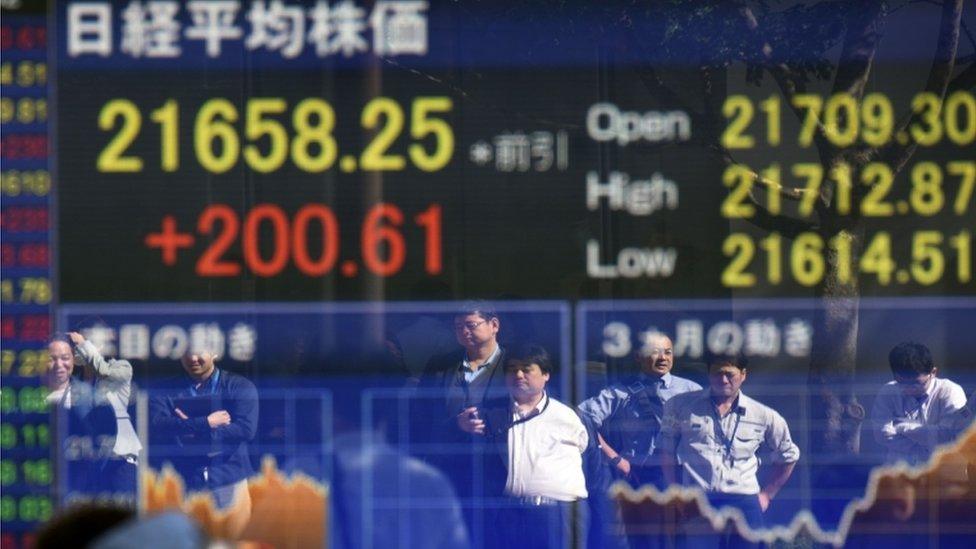 Pedestrians reflected in window with stock market figures in Tokyo on 23 October after Abe is elected