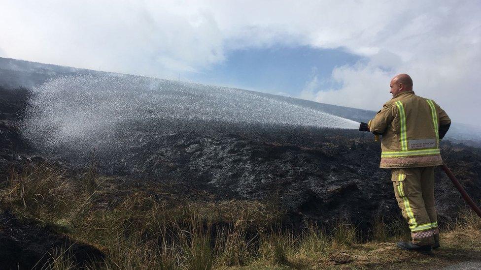 A firefighter hosing the moorland