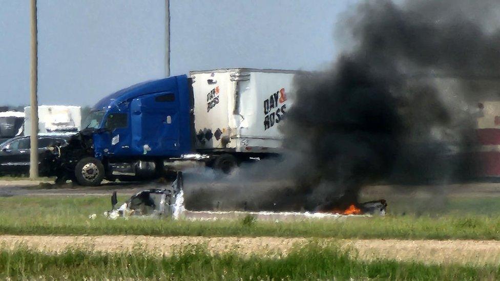 Smoke comes out of a car following a road accident that left 15 dead near Carberry, west of Winnipeg, Canada on June 15, 2023