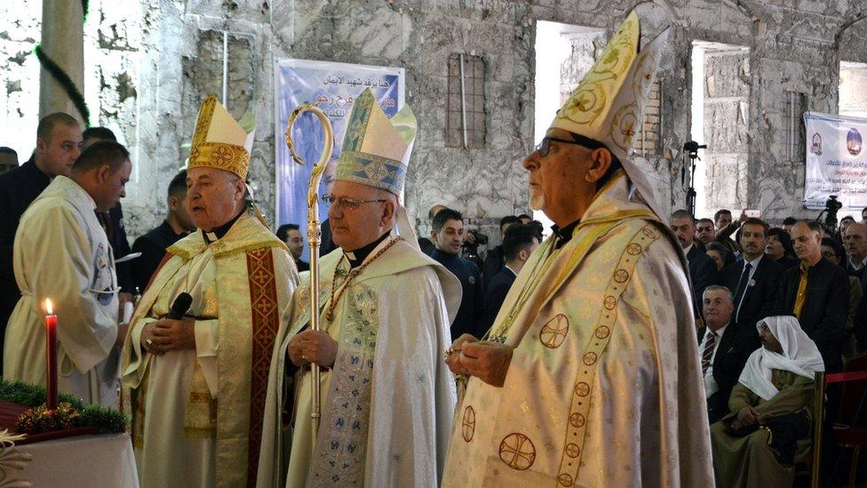 Iraqi priests lead the prayers during a Christmas mass at the Saint Paul"s church in Mosul city, northern Iraq, 24 December 2017